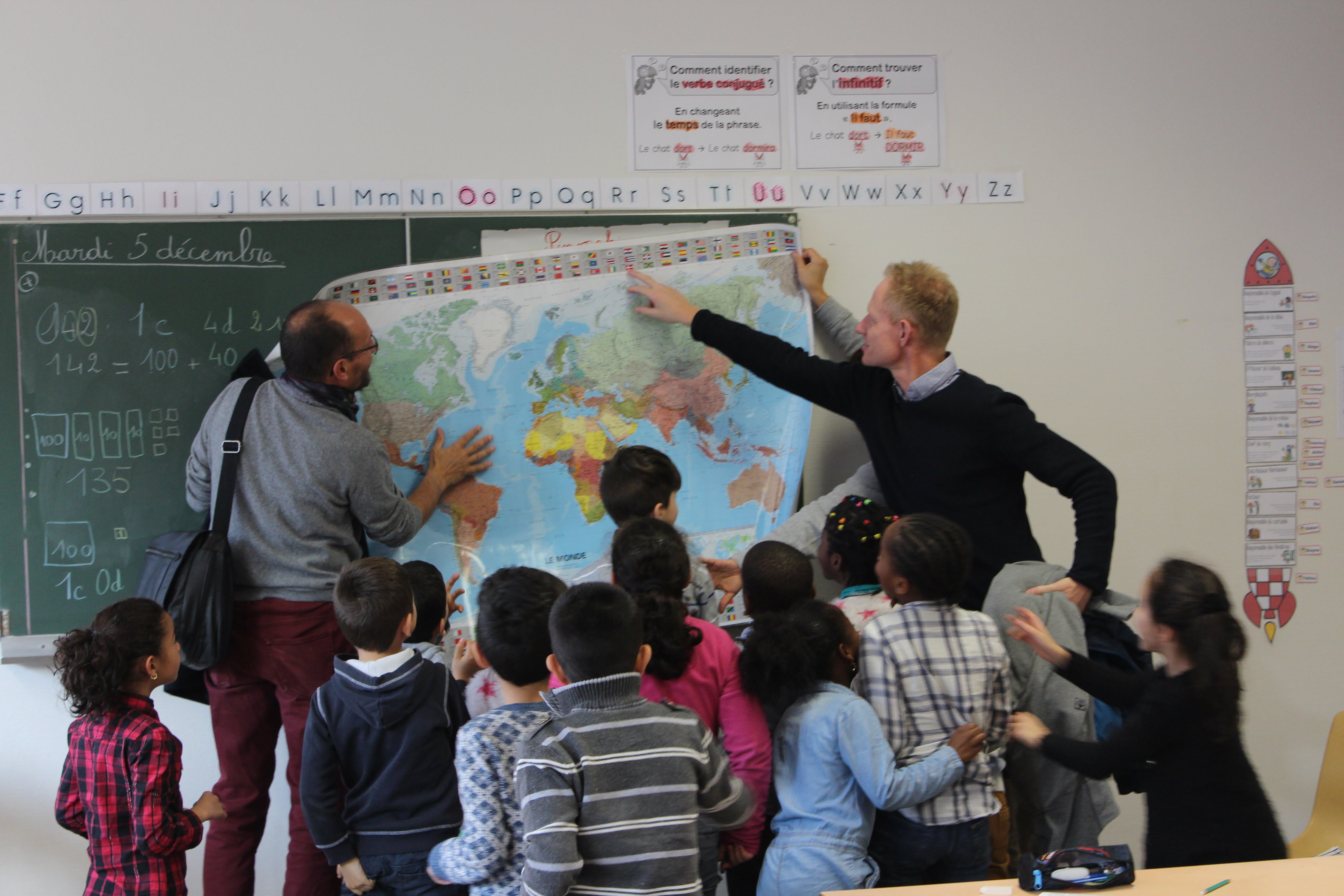 Børneflok og lærer kigger efter Danmark på kort